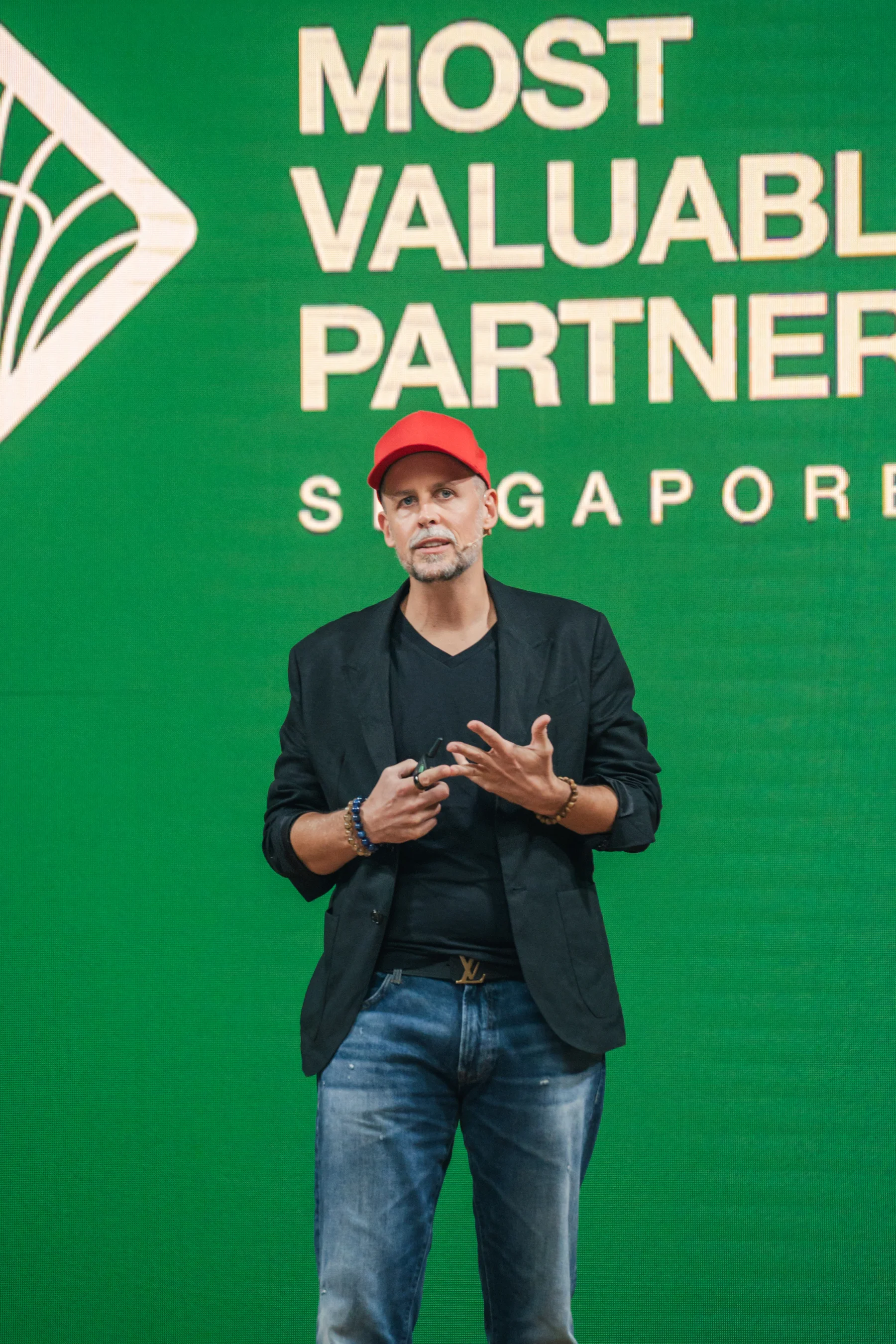 Sebastian Maier wearing a red cap and headset on stage